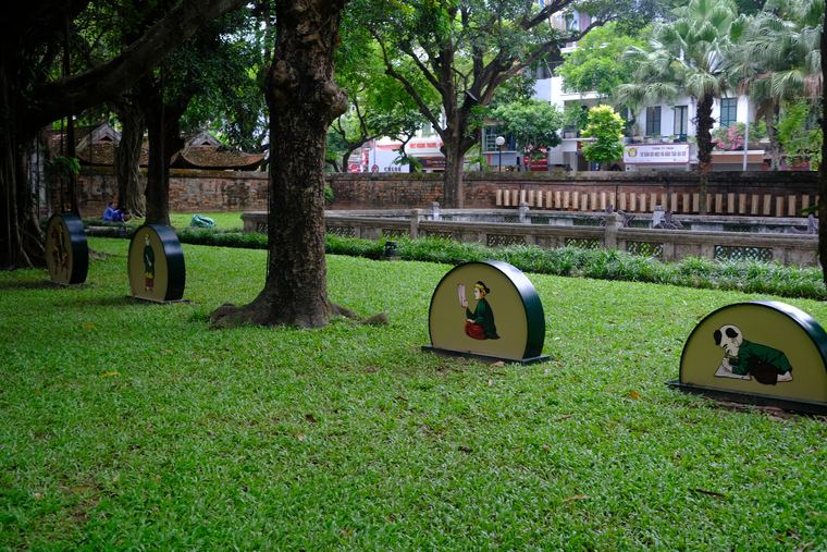 Curved green markers set on a lawn beneath old trees