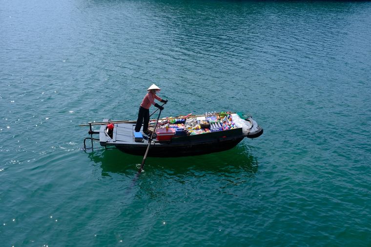 A woman rowing a laden boat across Ha Long Bay